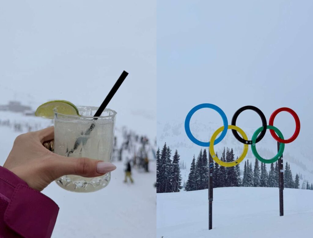 A hand holds a cocktail with a lime wedge in front of a snowy ski slope; beside it are the Olympic rings displayed outdoors in a snowy landscape with pine trees.