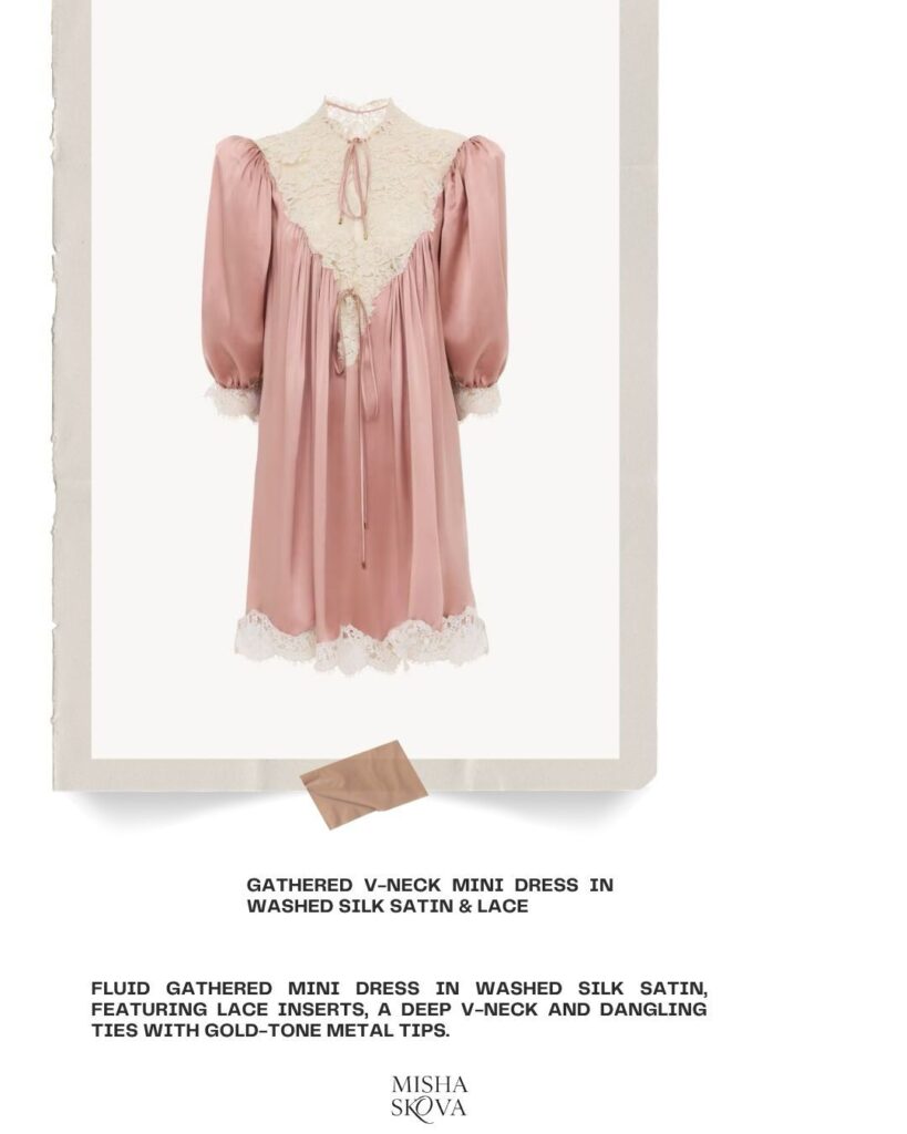 A blush pink gathered mini dress in washed silk satin with a deep V-neck, cream lace inserts, puffed sleeves, and gold-tone metal-tipped ties, displayed on a white background with a fabric swatch below.